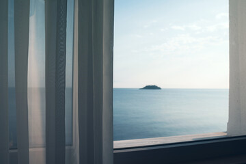 Fototapeta premium small ocean island seen through a window with transparent fabric curtains