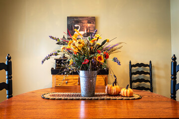 dinning room decorated for fall with flower bouquet centerpiece and pumpkins on oak table