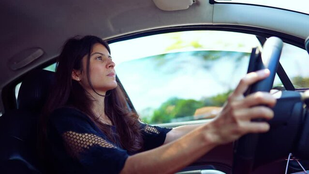 Concentrated young woman holding car steering wheel driving in high speed. Focused female driver on highway road traveling
