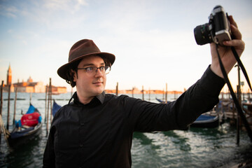 Vacationer in Venice takes a selfie in front of the canal with a camera