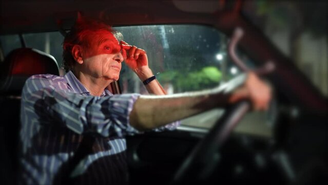 Pensive older man waiting in red light at night holding car steering wheel. Thoughtful senior person waits in signal