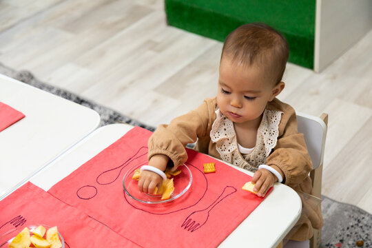 Toddler Eating Snacks By Table