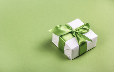 White gift box with green bow on green background. Gift box copy space