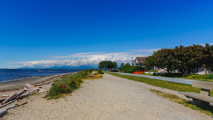 Public beach stroll at Crescent Beach, Surrey, BC, on a sunny summer day, with alpine mountains in...