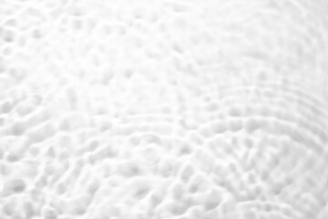 White-grey water waves in sunlight. Closeup of desaturated transparent water surface texture with splashes and bubbles.