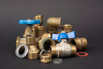 Metal sanitary tees, adapters for water supply pipes lie in a pile.