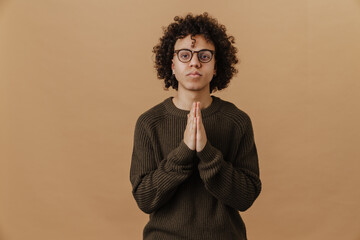 Young curly calm boy in glasses with folded hands