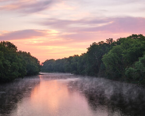 A stunning reflection of a pink and purple sunrise over there White River in Indiana. There is some mist on the water.  - obrazy, fototapety, plakaty
