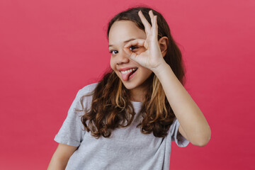 Young beautiful long-haired funny girl showing tongue and OK gesture