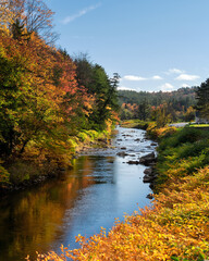 A beautiful river next to the highway in rural Vermont surrounded by a forest in beautiful autumn color. 