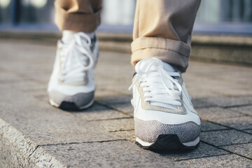 Fototapeta na wymiar Legs in beige pants and white sneakers