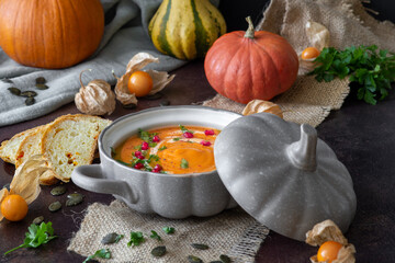 pumpkin soup in a bowl with coconut milk, decorated with pomegranate seeds and parsley