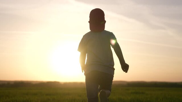 boy run. kid kid running a across the field in the park silhouette at sunset. happy family people in the park. boy run silhouette. happy childhood summer freedom fun concept. kid run