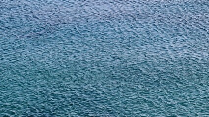 Genova, Italy- July 27, 2022:Panorama of the blue sea, light above the water, ocean sunrise. Some little waves in winter days. Clear sky reflected on the water.