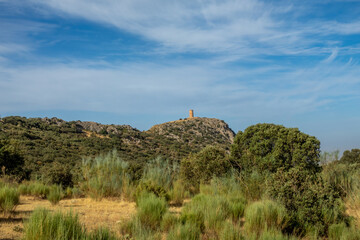Fototapeta na wymiar Atalaya de Deifontes (Spain) on a rocky hill surrounded by oaks on a sunny summer morning