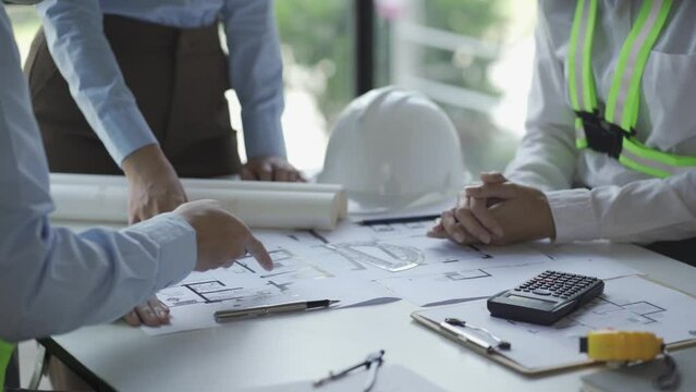 construction meeting construction with builders Architects and Engineers and inspector They were looking at the various planning blueprints in the office. 4K stock video clip.