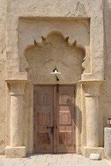 Vintage entrance to the oriental house with worn wooden closed doors decorated with carved sandstone columns and quaint arch. Typical middle eastern architecture. 