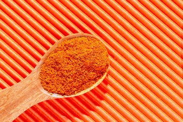curry powder in the wooden spoon, on orange background