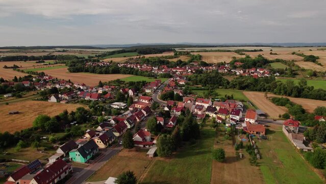 Aer ial view of a German village surrounded by meadows, farmland and forest in Germany.