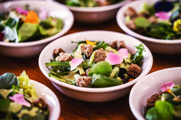 vegetable salad, vegetables and flowers. multiple salad bowls with arugula, flower petals, vegan toast