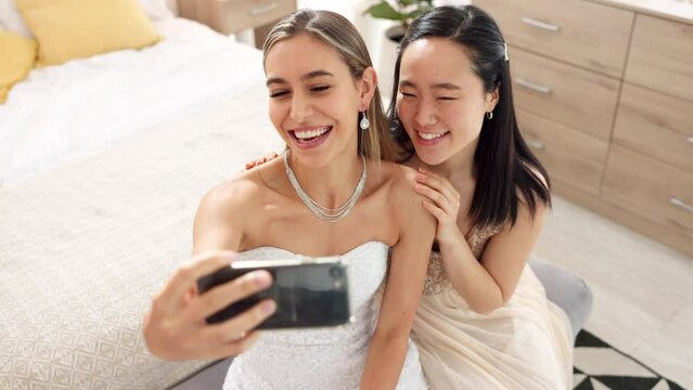 Bride, bridesmaid and selfie with phone, wedding and ring with a smile to post on social media. Happy woman and asian friend excited for marriage celebration with fashion white dress in a bedroom