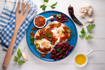 Ranch eggs with beans. Traditional Mexican recipe with fried eggs in a paella and corn pancakes