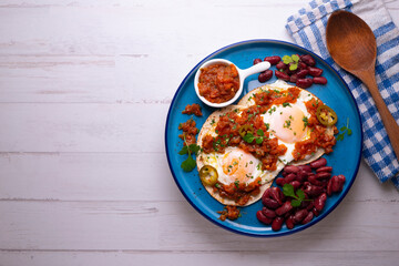 Ranch eggs with beans. Traditional Mexican recipe with fried eggs in a paella and corn pancakes