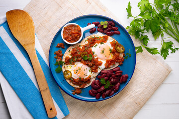 Ranch eggs with beans. Traditional Mexican recipe with fried eggs in a paella and corn pancakes