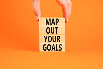 Support and map out your goals symbol. Concept words Map out your goals on wooden blocks on beautiful orange table orange background. Businessman hand. Business, support and map out your goals concept