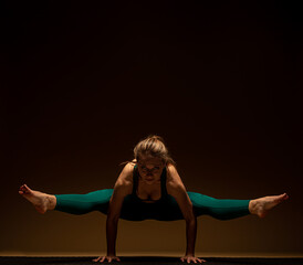 Doing the bakasana pose with her legs on the side while balancing