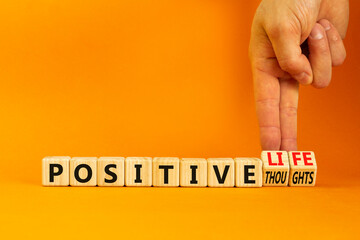 Positive thoughts and life symbol. Concept words Positive thoughts or Positive life on wooden cubes. Businessman hand. Beautiful orange background. Business positive thoughts life concept. Copy space