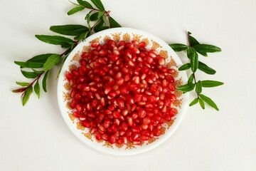 juicy fresh pomegranate seeds in dish and leaves isolated on white background,Top view,selective focus