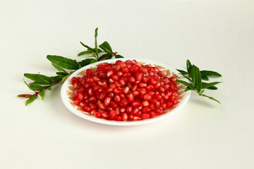 juicy fresh pomegranate seeds in dish and leaves isolated on white background,Top view,selective focus