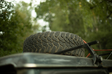 Wheel on roof of car. Spare tire on trunk. Transport for forests.
