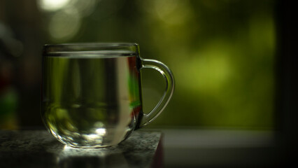 Glass with water on background of window. Water in cup. Transparent drink.