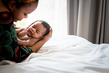 Obraz na płótnie Canvas an African baby newborn son, is 2 months old Lying on the hands of mother, in the bed, to relationship of family and newborn concept.