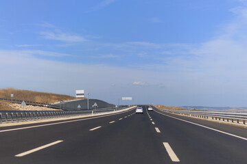 Fototapeta premium Highway wide road, transport and blue sky with clouds on a summer day