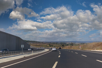 Fototapeta premium Highway wide road, transport and blue sky with clouds on a summer day
