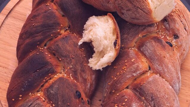 Ruddy challah baked with sesame seeds rotate in a circle. Medium plan