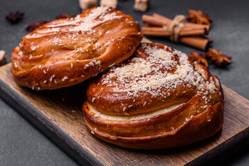 Delicious fresh crispy cinnamon buns sprinkled with coconut crumbs on a wooden cutting board