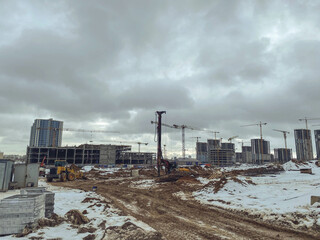 Fototapeta premium construction of houses, a shopping center from concrete blocks in the city. construction of a new residential quarter in winter. cranes and construction equipment erects a quarter