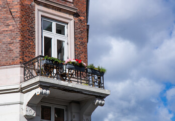 Cute old balcony with flowers and a window in an old blick house. High quality photo
