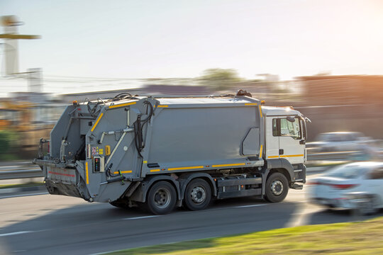 Recycling gray garbage truck driving on highway with motion blur speed effect.