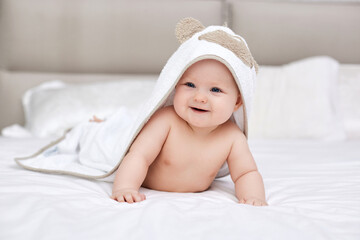 Fototapeta na wymiar adorable baby girl lies on a white bed with a towel