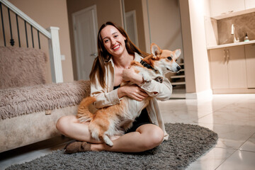 Attractive girl hug and play with corgi dog at home. Welsh Corgi Pembroke with his owner woman on the floor at living room