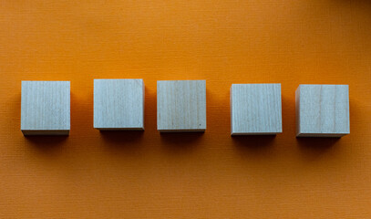 Five wooden cubes on orange background, mocap