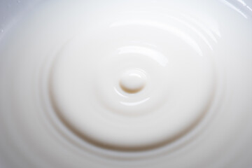 Closeup of drop of milk falling into milk bath