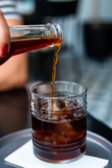 Pouring cold brew iced coffee in glass cup with ice cubes , coffee consept