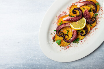 Octopus with potatoes and spices , on a light plate, top view, no people, homemade, close-up,