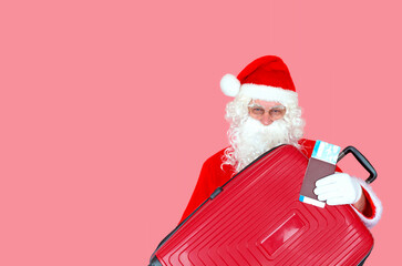 A cheerful man in a Santa Claus costume with a plane ticket and a suitcase in his hands, ready for a new journey to distribute gifts to children. The concept of New Year and Christmas